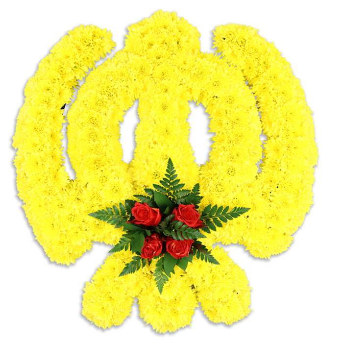 A sweeping, lovingly crafted Khanda emblem, formed from an abundance of bright yellow chrysanthemum heads, occupies the frame against a clean white field with a faint grey shadow that grounds the piece. The yellow chrysanthemums are arranged with meticulous attention to the symbol's proportions: the circular chakkar is smoothly curved, the two kirpans sweep outward in balanced arcs, and the central double-edged khanda is given a firm, vertical presence-together creating an impression of solemn dignity. At the core, where the lines converge, five to six rich red roses are gathered tightly and set into a cushion of deep green fern leaves; the contrast between the glossy, velvety roses and the matte, ruffled chrysanthemum surface creates a focused, heart-like centre. The textures are tactile in description: the chrysanthemum petals feel soft and slightly feathery, the roses dense and fragrant, the ferns cool and structured. The white backdrop intensifies the colour story so the yellow appears warm and consoling rather than bright, making the piece particularly appropriate for ceremonial displays, remembrance services or cultural events connected with the local Sikh community. Final finishing, from stem wiring to foliage placement, reflects the care of a local Highgate maker-Flowers Highgate would prepare such a tribute thoughtfully for deliveries to nearby venues such as Highgate Cemetery chapels or community halls. The overall effect is one of reverence and skilled craftsmanship: a floral emblem that speaks of honour, memory and communal support.