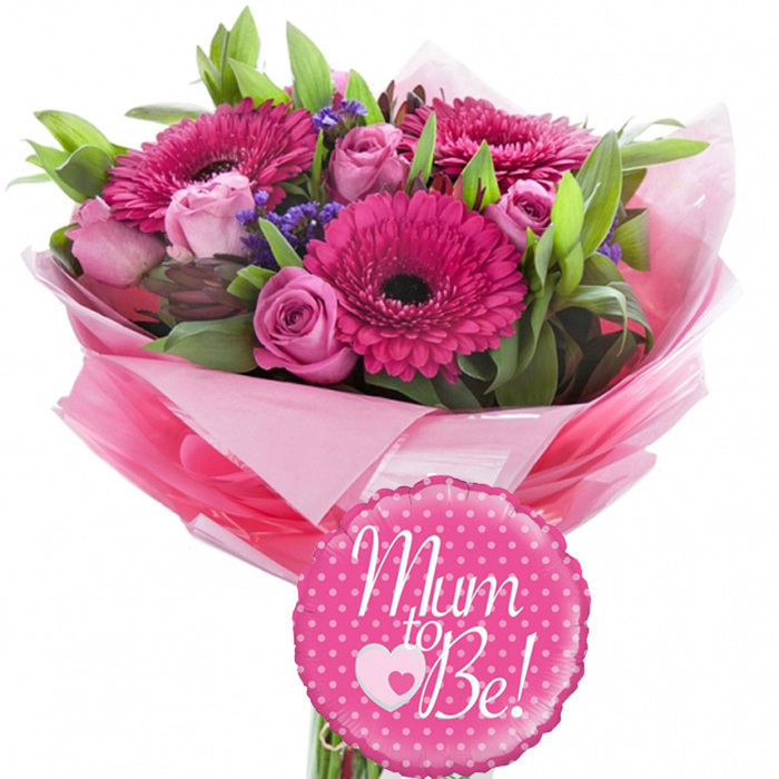 A charming baby shower bouquet brimming with pink blooms is shown against a bright white background, making every detail of the design easy to imagine. At its heart, vibrant fuchsia gerbera daisies stand proudly, each bloom perfectly round with a dark central eye that accentuates the vivid colour of the petals radiating outward. Encircling and weaving between the gerberas are pink roses in gentle, feminine tones, some no larger than a thumb as tight buds, others opening into soft spirals that reveal multiple layers of silky, slightly curled petals. Tiny purple filler flowers form a delicate veil throughout the arrangement, providing a muted lavender accent that breaks up the dominance of pink and evokes the peaceful corners of Highgate's gardens. Surrounding the flowers, lush green foliage helps structure the bouquet: long, slim leaves lend a sense of line and movement, while broader, deeper green leaves anchor the arrangement, contributing volume and a natural, garden-picked charm. The stems disappear into a generous wrapping of pink tissue paper, layered to create a rippled, ruffled effect, with shades ranging from pale pastel to stronger rose tones, all enclosed in a clear, glossy cellophane outer that gives the bouquet a finished, ready-to-gift appearance. Attached at the front is a small round foil balloon in bright pink, edged with a neat scalloped border and sprinkled all over with crisp white polka dots. Across the centre of the balloon, graceful white script reads Mum to Be!, and just between the words sits a small pink heart outlined by a larger white heart, subtly symbolising a baby held close. The overall scene conveys joy, love, and hopeful anticipation, making this arrangement ideal for celebrating a pregnancy announcement or baby shower in Highgate and nearby areas.
