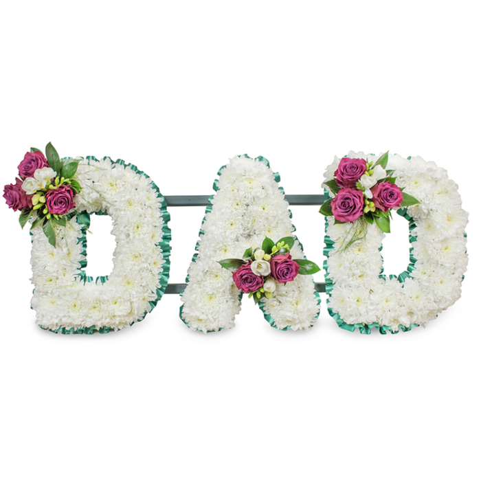 Carefully crafted by Flowers Highgate, this memorial lettering spells DAD in three solid, three-dimensional capitals, each letter formed from a dense mass of pure white chrysanthemums that provide a soft, voluminous texture evocative of quiet dignity. The sculpted letters are crisply defined by an emerald-green, pleated ribbon that traces outer and inner edges, offering a vivid, respectful contrast to the pale blooms. A discreet dark green support bar runs behind the letters, suggesting a firm, self-standing construction suitable for lay-down or easel display at a funeral service. Each letter receives a delicate accent-clusters of deep magenta roses in mixed stages of bloom, small white freesia-like sprays, and deep green foliage-placed with thoughtful symmetry: the first D's cluster sits on the upper left curve, the A's accent is cradled in the lower central V, and the final D mirrors the first with its bloom at the upper right curve. The arrangement's palette - pristine white, emerald green, and vibrant magenta - balances solemn respect with personal warmth, while the textures of fluffy chrysanthemum heads and velvet rose petals invite touch and memory. Under soft, even lighting against a clean white background the piece reads clearly from a distance, making it suitable for display at Highgate Cemetery services, village funeral chapels, or graveside gatherings in Waterlow Park's nearby surrounds. As a local florist we arrange careful delivery and placement for families in Highgate and the neighboring streets, ensuring the tribute arrives fresh, intact and ready to honour a beloved father.