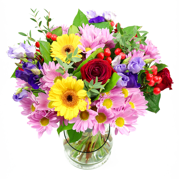 This photograph captures a full, artfully balanced bouquet resting in a clear glass vase against a neutral white background, a setting that allows the colours to stand out with clarity. At the centre of the design, deep red roses unfold with a velvety sheen, their tightly layered petals giving an impression of depth, romance, and careful craftsmanship. Framing these roses, two bright yellow gerbera daisies with dark brown-orange centres add a joyful, sunlit brightness, reminiscent of a late summer afternoon overlooking Highgate's leafy streets. Around them, a generous ring of soft pink and lilac-toned daisies or chrysanthemums offers a more delicate note, their slender petals and tiny yellow centres forming a gentle, cushion-like surround that softens the overall look. Winding among these blooms are elegant purple and lavender lisianthus, their bell-shaped flowers and slightly curled edges adding height, a cool colour contrast, and a subtle sense of movement, as if stirred by a light breeze. Bright red hypericum berries, scattered throughout the foliage, create small, rounded accents that bring both texture and a modern twist to the traditional blooms. The floral display is anchored by a mix of verdant greenery in varied shapes and tones: broad, deep green leaves lend structure at the base, while lighter, airier sprigs extend upward, echoing the natural abundance of nearby Highgate Wood. Through the transparent vase, the viewer can see neatly trimmed stems, arranged with precision in clear water, evidence of the florist's skill and the bouquet's freshness. The arrangement feels celebratory yet sophisticated, ideal for marking special milestones, offering congratulations, or simply brightening a Highgate townhouse or flat with a burst of colour and life.