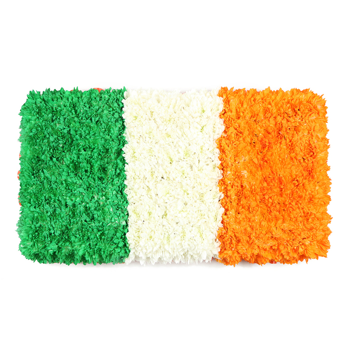 An elegant rectangular floral flag, carefully arranged to resemble the Irish tricolour, rests against a stark white background. The left green stripe is a lush field of small, densely packed blossoms-green chrysanthemums or carnations-creating a verdant, tactile surface; the center white stripe is a pale, cloudlike band of tightly clustered white petals; the right orange stripe glows with orange blooms, mirroring the same texture. The three color blocks align into equal vertical panels, forming a precise rectangle that honors flag proportions while celebrating handcrafted artistry. The greens evoke Irish Catholic tradition, the white stands for lasting peace, the orange for the Protestant community; together they symbolize unity and heritage. The white backdrop ensures the floral details pop, inviting the viewer to notice each petal and its subtle, immediate texture. Taken in a North London studio near Highgate Village, the arrangement embodies the care of a local florist who understands how such symbols resonate in community spaces, from parish halls to school celebrations. Available for same-day delivery across Highgate and neighbouring areas, this living banner is ideal for features on national identity, St Patrick's Day events, or cultural remembrance, marrying craft with meaning in a visually striking way.