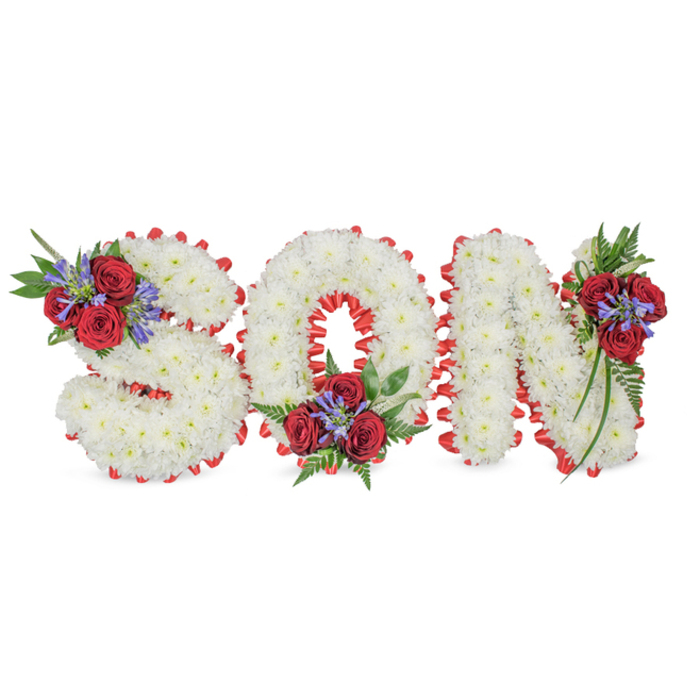 A poignant, meticulously formed memorial piece that spells SON in sculptural, three-dimensional letters, photographed against a simple white field. Each letter is built from a dense assembly of immaculate white spray chrysanthemums whose small blooms create a soft, cushiony surface and a gentle, reflective texture. The outer edge of every character is traced with a vivid red satin ribbon, banded and pleated to form a scalloped border that crisply defines each letter's silhouette and offers a striking colour contrast. Three floral accents punctuate the arrangement: on the S a compact spray of dark red roses paired with upright blue-purple Liatris and rich, fern-like greenery sits at the top-left curve; the O bears a corresponding cluster nestled in its lower centre; and the N carries a similar composition at its upper right, where foliage trails slightly to soften the vertical stem. The roses bring velvety depth and a faint sweet scent, the Liatris contributes spiky architectural rhythm, and the ferns add an old-world, comforting softness. The lighting is even and respectful, emphasising the purity of the white chrysanthemums and the saturated red trim. Designed for memorial displays in chapels or at gravesides near Highgate Wood or along Swains Lane, this piece reads as an intimate, traditional expression of love and mourning, crafted to honour a son with both dignity and tender attention to detail.