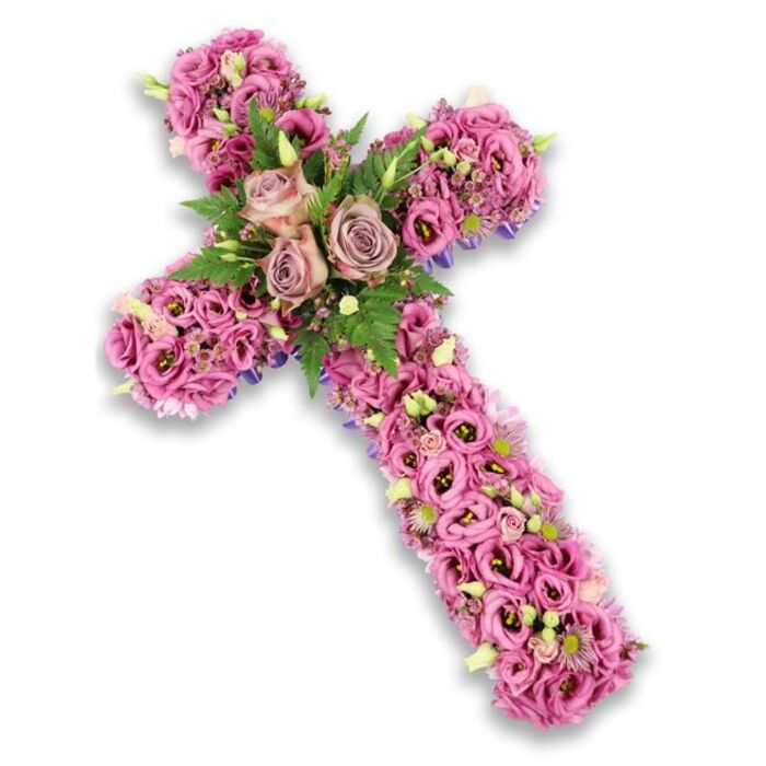 This image shows a graceful floral cross laid out against a pristine white background, illuminated so that each flower and leaf is clearly visible. The cross shape is strong and defined, yet softened by the dense coverage of blooms that fully cloak its structure. The colour palette is gentle and contemplative, with soft pinks, mauves, lilacs, and light purples flowing into one another like brushstrokes. Along the arms and stem, the cross is carpeted with Lisianthus flowers, their trumpet-shaped, delicately ruffled petals pressed close together, creating a lush and continuous texture. Some of these blooms are a faint blush pink, others shift toward brighter, more saturated tones, with darker centres that lend a sense of depth. At the point where the vertical and horizontal arms meet, three open roses in dusty rose and muted lavender-pink stand out as the central feature, their layered petals spiralling outward as if in quiet blessing. These roses are framed by feathery green fern fronds and smaller, more compact leaves, offering a refreshing contrast to the soft floral colours and recalling the calm greenery around Highgate Cemetery and local churchyards. Small filler flowers in pale pink, cream, and soft purple, along with tiny light green buds, are tucked throughout the design, adding intricate details that reward a closer look. Along the outer edges, faint glimpses of deeper purple ribbon or base material can be seen, gently outlining the cross's silhouette. It's the kind of thoughtful, handcrafted tribute a family in Highgate might choose for a funeral or memorial service, conveying love, respect, and spiritual hope through delicate, carefully selected blooms.