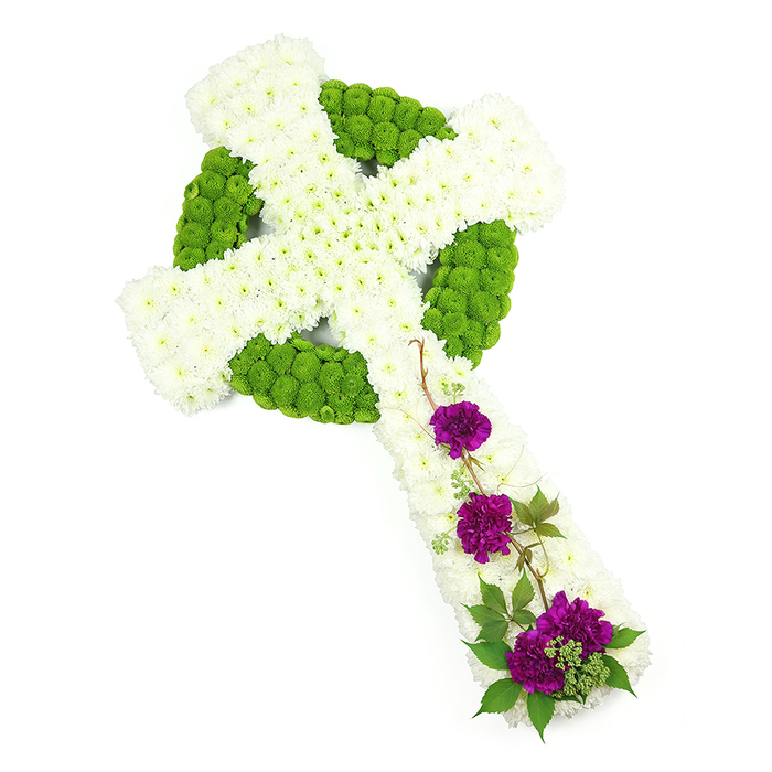 A beautifully composed Celtic cross made entirely from fresh blooms stands out against a plain white studio background, its balanced colours and textures suggesting both tradition and tenderness. The main body of the cross is crafted from countless small white chrysanthemum flowers, meticulously positioned so that their rounded heads create a thick, even layer along the vertical and horizontal arms. This white surface appears softly domed and plush, inviting the imagination to feel its gentle texture. Set within and surrounding this white field, bright lime green button chrysanthemums have been used to draw out the Celtic ring and interlaced patterns, forming a circular band around the intersection of the arms and highlighting key edges and segments. Their vivid green hue and compact, spherical shape give a subtle sense of movement, like new leaves against weathered stone in one of Highgate's quiet gardens. On the lower part of the vertical arm, three distinct clusters of deep purple carnations are carefully placed. The carnations' velvety, ruffled petals add depth and emotional warmth, standing in thoughtful contrast to the cool white and green. Around these purple accents, slender strands of dark green foliage and lightly twisting stems curve in a natural, almost wind-touched line, softening the crisp outline of the cross. The lighting is even and clear, allowing each bloom to be seen in the mind's eye, from the central circle to the tapered tips of the arms. This floral Celtic cross would make a poignant funeral tribute for a service near Highgate Cemetery or a local church, symbolising enduring faith, remembrance, and the cycle of life.