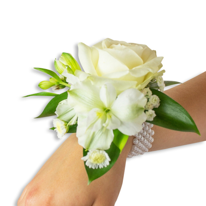 A refined wrist corsage composed of creamy white and green accents rests on a fair-skinned wrist, captured on a stark white background to emphasise every leaf vein and petal curve. The centerpiece is a perfectly opened ivory rose, its outer petals curling back to reveal a dense, textural core that reads as both soft and substantial. To the lower-left, a trumpet-shaped white alstroemeria or similar lily opens with gently fluted petals and a pale green-yellow throat, the subtle ribbing adding sculptural interest. Interspersed throughout are delicate sprays of baby's breath, their tiny white blossoms creating frothy pockets of translucence, while a small cluster of daisy-like blooms with clear yellow centres offers a petite, sunny contrast near the base. Fresh green buds-tight, glossy and edged with lime-suggest upcoming blossoms and provide vertical rhythm, balanced by broad, smooth, deep-green foliage that frames the flowers and holds the composition together. The corsage is anchored by a multi-strand pearl wristlet: many lustrous, round faux pearls threaded on elastic that encircle the wrist with comfortable refinement and act as the decorative band for the floral cluster. The light is soft and even, revealing the pearly gleam and the rose's creamy warmth, and the overall scent palette would be faintly floral and green, like a morning walk near Highgate Cemetery or through the lanes toward Archway Road. This piece feels crafted for formal moments-weddings, proms, anniversaries-where classic materials and subtle modern styling meet.
