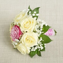 Picture carrying through Highgate Village a bouquet that whispers of early morning light and timeless romance-creamy roses, velvety and full, quietly encircling a magenta-pink rose glowing with intensity and promise. This arrangement, crafted for special moments by a Highgate floral expert, is interlaced with fine sprays of baby's breath, which lighten the bouquet and echo the soft mists that rise over Hampstead Heath at dawn. Deep green leaves create a grounding foundation, recalling the rich greenery along North Road and the rolling slopes of Highgate Wood. Wrapped in a bright, fuchsia-pink satin ribbon, the stems feel cool and secure to the touch, while a thread of pearlescent white beads spirals along their length, adding a subtle glimmer like morning dew in the park. Resting on a refined, neutral fabric, the bouquet's gentle textures and layered scents evoke both excitement and serenity-perfect for a bridal party, anniversary, or a moment of celebration in Highgate's storied surroundings. The artistry of each element, from the fresh blooms to the carefully selected palette, reveals a deep appreciation for both tradition and the unique character of the local North London community.
