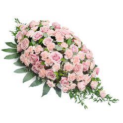 This image features an elegant sympathy spray, photographed on a clean white background so that every blossom and leaf stands out clearly. The arrangement is shaped in a classic casket spray or teardrop form, full and rounded at the top left and then gently tapering to a soft point at the lower right, giving a sense of gentle movement across the frame. The main body of the design is densely composed of soft pink roses, some fully open and showing their intricate spirals of velvety petals, others slightly more closed, adding layers of tone from blush to muted rose. Interwoven throughout are clusters of light peach-pink carnations, their delicately frilled petals bringing a soft, textured quality that makes the arrangement appear plush and comforting. The flowers are framed by rich green foliage: broad, oval leaves that create a strong, dark base around the pastel centre, and lighter, more slender sprigs that arc and trail from the edges, particularly at the pointed tip, adding an airy, cascading effect. The overall mood is one of calm, respectful beauty, the sort of arrangement a family in Highgate might choose for a funeral at a local church or a memorial gathering near Highgate Wood. While the photograph is still and composed, the spray itself feels quietly alive with meaning-a thoughtfully crafted tribute that conveys sympathy, warmth, and remembrance without being overly ornate. It reflects the touch of experienced florists who understand how to balance colour, form, and texture to create a final farewell that feels both personal and peaceful.