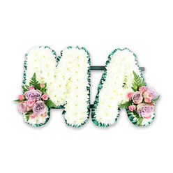 The image shows a lovingly crafted funeral tribute spelling the word MA in large, bold letters made from pure white flowers. Each capital rests on a plain white backdrop so that the structure, colours, and textures stand out clearly. The letters are filled with small white chrysanthemums, laid so closely together that no gaps are visible. Their many-petalled heads create a plush, almost velour-like surface that looks soft to the touch, as if it might yield slightly beneath a resting hand. Around the perimeter of both the M and the A runs a dark green pleated ribbon, carefully folded in small, regular ruffles. This satin border frames the floral surface like a picture frame, giving strong definition and echoing the deep greens of the gardens and tree-lined streets near Highgate Village and Swain's Lane. At the base of the left side of the M and the right side of the A, the chrysanthemums are softened by small accent bouquets. These are composed of blush-pink roses and gentle lilac roses, each bloom layered with smooth, spiralling petals. Tiny pink spray roses cluster between them, creating a sense of fullness and delicate detail. Wisps of greenery and airy fern fronds extend from beneath the roses, adding a fresh, natural line and a slightly wilder note, like foliage glimpsed along the paths of Highgate Wood. The tribute feels tailored yet heartfelt, the kind of arrangement a family might choose to say goodbye to a mother, mama, or someone whose initials form M.A. at a funeral service, graveside committal, or memorial gathering in the Highgate area.