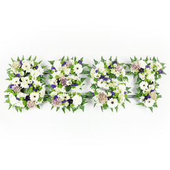 An intimate, tapestry-like floral tribute spells DAD in three bold letters, each one formed from a soothing palette of whites, purples, and fresh greens, set plainly against a bright white background. The composition is textural and deliberate: plush ivory gerberas and velvety chrysanthemums provide strong focal points, their round faces bright and consoling, while pastel coffee roses introduce a soft, warm beige-pink that feels quietly nostalgic. Alongside these are delicate lisianthus and billowy carnations, their layers of petals creating a tactile softness you can almost touch. Small clusters of violet statice and deeper mauve filler flowers are threaded through the letters, offering respectful colour notes that read as dignified and heartfelt rather than flamboyant. A crisp border of lively fern leaves outlines each letter, the fronds' serrated edges lending movement and life to the otherwise composed shapes, while green button chrysanthemums sit tucked among the blooms to add compact freshness and a natural contrast. The letters appear to rest on a subtle dark base, visible only in glimpses where the florals part, which helps keep each initial clear and readable. Imagine the faint, clean scent of fresh roses and chrysanthemums in a cool room - that understated fragrance that brings quiet comfort. As someone who arranges memorial pieces for families around Highgate and the nearby Archway and Hampstead borders, I find that these personalised letters provide a tangible expression of love and remembrance, an embrace of flowers that honours a father with dignity and warmth.