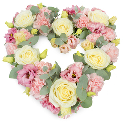 Set against a bright white backdrop, this heart-shaped funeral wreath appears as a gentle, floating symbol of love, much like a quiet pause in the middle of busy life around Highgate Village. The heart is completely filled with flowers, with no visible base, giving a luxurious, almost cushion-like impression. Cream and pale yellow roses stand prominently throughout the design, their velvety petals unfurling from tightly swirled centres into perfectly rounded blooms that anchor the eye. Between them, clusters of pastel pink carnations fill the spaces, their frilled petals softening every edge and creating a comforting sense of abundance. Richer rose-pink and mauve lisianthus blooms are interspersed more sparingly, providing deeper notes of colour and gentle variation in shape, as their slightly flared blossoms contrast with the neater forms of the roses and carnations. Stems of eucalyptus weave through the arrangement, their silvery-green, rounded leaves adding a cool, clean contrast to the warm petals and outlining the heart's graceful curve. Small yellow-green buds punctuate the pastels with a suggestion of renewal and quiet hope. The overall palette is delicate and harmonious, evoking feelings of peace, tenderness, and heartfelt remembrance. This floral heart would suit a Highgate funeral service, crematorium farewell, or a memorial gathering in one of the area's historic churches, offering a soft, visual way to honour a loved one. Its craftsmanship reflects the practiced hand of an experienced florist: each flower placed thoughtfully so that the heart reads not just as an arrangement, but as an expression of care, gratitude, and enduring affection.