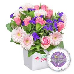 An exuberant celebration of love unfolds in this radiant engagement bouquet, expertly arranged by a Highgate florist. The bouquet marries pink roses-buds at various stages, petals unfurling in creamy ribbons-with moonlit gerberas in pale blush that feel airy and buoyant, their soft edges catching lamplight as they fan outward. Deep purple statice threads its brilliance through the arrangement, a bold whisper of contrast that enriches the overall palette. Generous green foliage-sage-toned leaves, glossy sprays, and ferny sprigs-provides a lush, natural backdrop that makes the blooms stand out as a chorus of pink and lavender. The blooms are hosted in a pristine white square presentation box, whose front bears a subtle emblem: a red rose icon paired with green script, signaling a refined, boutique touch. At the side, a round foil balloon peeks into the frame, its surface gleaming with a central purple disc carrying the declaration 'You're Engaged!' in silver type, while a playful golden 'O' in You're adds a glint of romance. Surrounding the central design, a soft halo of pastel hearts and silver stars dances along the balloon's edge, underscoring the promise of a shared future. This composition-modern, joyful, and warmly intimate-reads as a perfect congratulation for a newly committed couple. Available for delivery across Highgate and neighboring districts such as Archway, Crouch End, and Muswell Hill, it brings bright celebration to living rooms and dinner tables alike.
