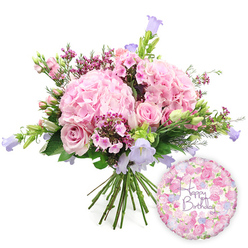 A lavish, hand-tied bouquet paired with a birthday balloon is shown against a clean white background, every detail crisply defined as though displayed in a Highgate flower studio. The bouquet forms a generous dome of colour and texture, anchored by several large hydrangea heads in a gentle blush pink. Each hydrangea is composed of countless small, rounded petals, overlapping to create a plush, pillow-like effect that gives the arrangement its soft, romantic heart. Threaded gracefully between these voluminous blooms are pale pink roses, in various stages from tightly wrapped buds to more open, layered flowers. Their spiralling centres and velvety petals add a sense of traditional elegance, reminiscent of classic rose gardens near Highgate Cemetery and the surrounding tree-lined streets. Adding contrast and a brighter pop of colour, clusters of vivid fuchsia or magenta waxflowers are interspersed throughout, their tiny cup-shaped blooms and buds introducing fine detail and a more playful note. Rising from the body of the bouquet, slender stems of campanula carry bell-shaped flowers in soft lavender and periwinkle hues, their vertical lines lifting the eye and balancing the rounded hydrangeas with a light, airy feel. Around the outer edges, a mix of lush green foliage wraps the flowers, including broader, darker leaves and more delicate, slender greenery, which helps to frame the pastel palette and highlight the freshness of the stems. The gathered stems are clearly visible at the base, bound tightly in the classic hand-tied style, ready to be placed in a vase on a windowsill overlooking Highgate's rooftops. To the lower right of the bouquet, a round foil balloon adds a celebratory finishing touch. Its surface has a soft, metallic sheen and is patterned with tiny roses and floral motifs in pink, cream, and lilac tones, mirroring the colours of the bouquet. In the centre of the balloon, the phrase "Happy Birthday" appears in graceful purple script, giving a clear, joyful message. The overall impression is one of affectionate celebration, a complete birthday gift that blends fresh flowers with a cheerful, coordinating balloon.