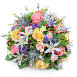 Set against a bright white backdrop, this lush, rounded bouquet appears almost like a living sculpture placed on a Highgate windowsill, its rich mixture of colours and textures radiating quiet celebration. At the centre, garden roses in soft pastel tones-delicate pink, mellow yellow, and creamy peach-form a generous core. Some roses are fully open, their layered petals spiralling outwards in intricate whorls, while others remain partially closed, their centres softly concealed. Interwoven among the roses are airy clematis flowers, their slender star-shaped petals shaded in white and pale lavender, each bloom anchored by a bright yellow or creamy centre that brings subtle focus. Standing proud above the softer forms, blue eryngium, or sea holly, delivers a bold, structural accent; its thistle-like, metallic blue heads add an intriguing textural contrast that feels at once contemporary and natural, echoing the character of nearby Waterlow Park. Deep purple lisianthus blooms are tucked throughout the bouquet, with some still in tight ruffled buds and others gently open, contributing a velvety depth to the overall palette. Scattered clusters of smooth red hypericum berries punctuate the design, offering bright, cheerful notes against the gentle pastels. A variety of greenery completes the arrangement: broad, glossy leaves provide a solid foundation, while finer, feathery foliage and hints of darker, almost burgundy leaves weave between stems, creating layers of depth and shadow. Soft, even lighting reveals the bouquet's freshness and form, producing a faint, rounded shadow beneath it. The result is a beautifully balanced composition, ideal for anniversaries, birthdays, or thank-you gestures, and perfectly suited to same-day delivery around Highgate's leafy streets.