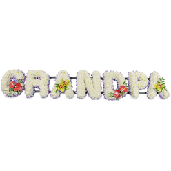 This photograph presents a lovingly crafted funeral tribute that clearly spells the word GRANDPA in large, capital letters arranged in a steady horizontal row, ideal for resting alongside a coffin in a Highgate chapel or crematorium. The overall impression is one of calm strength and tenderness. Each letter is completely filled with tightly clustered white chrysanthemums, the flower heads domed and uniform, giving the surface of the tribute a soft, quilted look that seems almost touchable. The pristine white blooms suggest purity, peace, and the quiet dignity of farewell. Just beneath the flowers, a slim border of pale lavender or lilac ribbon encircles the base of each letter, adding a delicate wash of colour and helping to define the word against the simple white background of the photograph. Dark green bars, almost hidden from the front, connect the letters and provide essential support so the piece can be moved and displayed safely. Small, vivid sprays of flowers interrupt the white at four points along the tribute: on the G and the D, deep red anthuriums with glossy, heart-shaped petals and bright yellow centres are nestled amid polished green leaves and touches of purple filler, creating strong, emotional focal points. On the first and last A, the tribute softens with clusters of yellow-green orchids whose petals arc gracefully, their fresh lime tones lifting the design. Together, these accents add rhythm and personality, suggesting different aspects of a grandfather's character-strength, warmth, and gentleness. Crafted with the care of an experienced local florist, this arrangement feels like a personal message of love from a family in Highgate or the surrounding streets of Muswell Hill and Crouch End.
