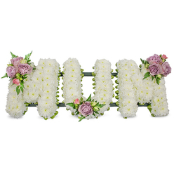 This carefully composed sympathy arrangement forms the word "MUM" in three substantial letters, each entirely covered in tightly packed, pristine white chrysanthemums or similar spray blooms to achieve a uniform, feather-soft texture. The chrysanthemums' crisp white tone communicates purity and calm; the dense petals are wired and secured to a discreet, dark green base that peeks through only as a thin outline beneath the blooms, confirming the structural support and handcraft behind the tribute. To bring warmth and gentle colour, three small clusters of lilac-lavender roses and pale pink rosebuds are artfully positioned: the first on the upper left limb of the left-hand "M", the second tucked into the soft curve at the base of the central "U", and the third adorning the upper right arm of the right-hand "M". Each rose cluster is complemented by fresh green foliage and delicate fern sprigs that add movement and a natural rhythm across the letters. The pastel roses provide a soft visual rhythm against the snow-white field, their velvet petals opening to reveal tender centres that contrast with the chrysanthemums' more matte surface. A subtle, ribbon-wrapped or mossed frame in deep green links and stabilises the letters, suggesting a funeral standing tribute prepared with professional care. The arrangement sits in gentle, diffused light, carrying a faint floral and green scent, and reads as a calm, respectful memorial-an arrangement a Highgate family might choose for a church service, chapel, or graveside at the local cemetery, created with steadiness and sympathy by an experienced local florist.