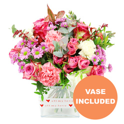 This image shows a romantic, hand-arranged bouquet brimming with fresh flowers, set in a modern square glass vase and photographed against a clear, white background. The colours lean towards pink and purple, with lush roses taking centre stage in tones from deep fuchsia to soft shell pink. The rose petals look velvety and layered, some edged with deeper colour so that each bloom seems to glow from within. Interlaced among them are ruffled carnations in coral, peach-pink, and delicate blush, their frilly petals adding texture and a sense of movement as they fan out from the centre. Scattered throughout are dainty daisy-style chrysanthemums in lavender and gentle lilac shades; each has a vivid green centre that pops brightly, adding a joyful spark to the arrangement. Creamy white accents and lighter blooms help to balance the stronger shades, ensuring the bouquet feels light-hearted rather than heavy. The foliage is as thoughtfully chosen as the flowers: rounded eucalyptus leaves in a subtle silvery-green, richer glossy greenery, and a few warm reddish-brown sprigs create a layered, natural frame, reminiscent of the greenery around Highgate's garden squares and tree-lined streets. At the base of the vase, a tidy white band encircles the glass, decorated with small red hearts and the affectionate wording "all my love," making the romantic intention unmistakable. In the bottom right of the image, a bold orange circular graphic clearly states "VASE INCLUDED" in white capital letters, so you can easily imagine this bouquet arriving at a Highgate doorstep already arranged and ready to enjoy. The mood is warm, caring, and slightly whimsical, perfect for anniversaries, Mother's Day, birthdays, or simply sending a little love across North London.