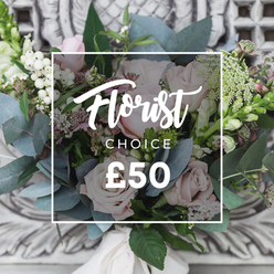 This loose, romantic bouquet feels like an English cutting garden brought indoors: voluptuous blush roses with soft, layered petals form the visual centre, their pale pinks mingling with subtle hints of deeper berry tones that give the composition depth. Interspersed through the arrangement are round white berries that catch the eye like tiny lights, and delicate sprays of white filler-likely waxflower or astrantia-that breathe openness into the design. The eucalyptus provides a cool, silvery-green backdrop, its rounded leaves creating soft, sculptural planes and adding a refreshing, herbal aroma when the bouquet is handled. Slim green-and-white flower spikes peek from either side, lending graceful height and an informal, slightly wild rhythm. Tied by hand with a cream-coloured ribbon, the stems suggest a bespoke florist's touch, the sort of care we take when preparing bouquets for local deliveries across Highgate and neighbouring Hampstead Heath. The picture is composed against an understated carved-stone background in warm neutral tones, seen slightly out of focus so the flowers remain the star. Over the arrangement a neat white frame contains the words "Florist" in flowing script, "CHOICE" in sans-serif, and the price "£50," indicating a thoughtfully curated option. In soft ambient light the arrangement reads as soothing and enlivening at once-a perfect offering for milestone birthdays, a new-home welcome, or simply to bring a calm, refined beauty into someone's day.