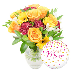 This image presents a lovingly composed floral gift: a clear glass vase reveals crisp, water-filled stems and supports a lush arrangement that feels both elegant and homey. Dominating the scene are large roses in warm orange and peach hues, each bloom unfurling in layered spirals that catch the eye and release a soft, classic perfume. Nestled among them, bright yellow gerbera daisies shine like small suns with their dark centres, providing a playful counterpoint to the deeper, ruffled burgundy carnations whose velvety petals add weight and romantic richness. Whispering through the arrangement are sprays of delicate white alstroemeria - slender, freckled petals that introduce lightness and a refined texture. Lush green foliage, from glossy broad leaves to delicate fern-like sprigs, frames the flowers and gives the bouquet a freshly-gathered-from-the-garden feel. A round white foil balloon sits to the bottom right, partially overlapping the vase; its surface is dusted with gold and fuchsia polka dots and tiny hearts, while the centre bears the affectionate inscription "best Mum" in flowing hot-pink script. The overall impression is one of thoughtful celebration - a floral ensemble that would make a kitchen on Muswell Hill or a living room near Highgate Village bloom with warmth. As a local florist in the Highgate area, I crafted this pairing to read clearly in photographs and in person: vivid colour, tender texture, and a personal message that feels handwritten and sincere.