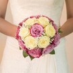 Reflecting the timeless elegance of weddings in Highgate, this evocative photo presents a bride's hands embracing a perfectly rounded bouquet-each detail designed with thoughtful expertise. At its core, creamy lemon-yellow roses and striking fuchsia blooms, tinged with nuances of mauve, create a striking interplay of colour and emotion. Wisps of white gypsophila flicker among the roses, lending lightness and subtle intricacy to the arrangement, while emerald-toned leaves provide grounding and organic texture, echoing the verdant greenery of Highgate's streets and parks. The bride, her forearms visible and gently curving at either side, frames the bouquet above a softly flowing ivory gown adorned with swirling lace-its motifs as delicate as the blooms themselves. Soft daylight flows across the flowers and fabric, illuminating every curve and petal with a sense of renewed promise. The softly blurred background evokes the serenity of Highgate Wood, allowing the vibrant florals to stand centre stage as emblems of commitment and celebration. For any couple longing for that perfect union of classic beauty and neighbourhood soul, this photograph evokes the heartfelt artistry and warmth synonymous with weddings in Highgate.