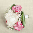 Resting on a pale, linen-like surface with a subtle weave, this elegant bouquet is photographed from above, allowing its carefully balanced design to unfold. At the heart lies a single, sumptuous creamy white peony, its petals densely packed and gently rippling outward, forming a plush, cloud-like sphere that feels soft and luxurious. Nestled closely above and below are two striking pink roses, their centres tightly coiled in perfect spirals, with petal tones that shift thoughtfully from gentle, romantic pink near the centre to deeper, more intense fuchsia at the edges, adding both warmth and sophistication. Throughout the bouquet, light sprays of white baby's breath, also known as gypsophila, create a fine mist of tiny blossoms, each one like a pinpoint of light that softens the stronger shapes and adds a delicate, floating quality. At the base, glossy dark green leaves fold around the stems, curving like smooth ribbons and forming a strong, architectural cradle that contrasts beautifully with the airy blooms. The stems themselves are neatly aligned and wrapped in a smooth white satin ribbon, suggesting a hand-held design ready for a Highgate bride or an anniversary celebration overlooking Hampstead Heath. The lighting is gentle, as if filtered through a nearby window on a calm morning in North London, highlighting the creamy tones, pink hues, and bright whites without harsh shadows. Crafted with care that feels very much in tune with Flowers Highgate's attention to detail, this bouquet carries a sense of romance, purity, and quiet celebration, ideal for weddings, vow renewals, or heartfelt gifts delivered around Highgate and neighbouring streets.