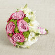 Laid gently across a pale, textured cloth, this bouquet has the composed elegance of a Highgate bride pausing on the steps of a historic villa. The central roses are full and open, their petals moving from a soft, powdered pink inside to a more saturated, almost fuchsia hue tracing the outer edges, giving each bloom a sense of inner glow. Around and between them nestle lime green button chrysanthemums, tight globes of tiny florets that introduce a vivid splash of colour and a playful, tactile surface. To the right, white lisianthus spills outward in a loose, graceful cluster, some flowers ruffled and fully unfurled, others held in slender buds that taper gently, touched with hints of cream. This arrangement of colours-romantic pink, lively green, and serene white-evokes both freshness and refinement, like the blend of old architecture and leafy avenues that characterises Highgate. The stems are aligned and bundled to form a smooth handle, carefully wrapped in blush pink satin ribbon that catches the light with a subtle sheen. Encircling the ribbon, multiple strands of luminous white pearls are coiled in even, deliberate loops, creating an accent that feels classic, almost heirloom-like, as though passed down through generations for special occasions. The neutral background fabric, probably linen or a similar material, has a fine crosshatch weave that adds quiet texture without competing for attention. This bouquet would suit images or descriptions of wedding flowers and special event arrangements created for ceremonies in Highgate, capturing both the romance of the day and the meticulous work of an experienced local florist.
