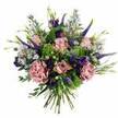 A lush, romantic bouquet fills the frame, photographed against a crisp white background that lets its pastel pinks, deep purples, and bright greens stand out with gentle clarity. At its heart, clusters of roses in soft blush and pastel pink unfurl with a sense of ease, their petals layered in intricate spirals that evoke tenderness and quiet affection. Threaded among them, full-headed carnations in dusty rose and mauve add a rich, frilled texture, making the arrangement appear generous and comforting, like a floral embrace. Shooting upward from between these rounded forms are graceful spires of deep violet Veronica, their slender, textured tips lending height and an almost painterly movement, as though the bouquet is stretching towards the light. Around and between the focal blooms, smaller clusters of velvety purple lisianthus nestle in, alongside delicate sprays of daisy-like aster flowers in soft lavender-blue, each with a tiny sunny centre that adds a hint of playfulness. The blossoms sit within a nest of greenery: bright lime-green textural filler and vibrant chartreuse tufts bring brightness and lift, while softly curving eucalyptus and other sage-green foliage introduce cooler, calming tones and a subtle, fresh scent. At the base, the stems are visible and neatly tied, giving the impression of a bouquet just handed over the counter by a Highgate florist. The whole arrangement feels like a gentle celebration-perfect for expressing love, saying thank you, or simply bringing beauty into a home near Highgate Woods, Waterlow Park, or the tree-lined avenues of N6, capturing a modern yet timeless floral style that suits both everyday gifting and special occasions.