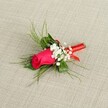 A single fuchsia rosebud boutonnière lies diagonally across a softly textured, light beige fabric, the kind of linen you might see in a Highgate Village boutique. The rosebud is tightly furled, its deep pink petals saturated with colour and catching the bright, even light so that every curve looks velvety and smooth. Clusters of tiny white baby's breath nestle around the rose, the minuscule blossoms forming a cloud-like halo that softens the overall look and adds a gentle contrast to the bold central bloom. Fine, feathery fronds of bright green foliage, reminiscent of asparagus fern or delicate ruscus, fan out from behind, giving the boutonnière a light, airy frame and suggesting movement, as though it has just been pinned to a lapel for a ceremony in Waterlow Park. Beneath the flowers, the stems are neatly gathered and wrapped in a slim, glossy red satin ribbon, wound carefully and firmly so no stray ends show, adding a subtle shine and an extra pop of colour that echoes the rose. The looped or tucked finish of the ribbon shows an artisan's hand, hinting at the care and precision that went into its creation. The neutral background keeps the eye focused on the fresh, dew-bright flowers, making this boutonnière feel timeless and romantic, perfectly suited for a groom or guest heading to a Highgate wedding, prom, or formal celebration along the leafy streets and historic lanes of North London.