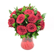A lush, romantic bouquet of around a dozen deep red roses stands proudly in a ruby-red glass vase, set against a crisp white studio background that makes every petal glow. Each rose is fully open but still wonderfully structured, its velvety petals curling in perfect spirals toward the centre, creating that classic, luxurious rose texture you can almost feel with your fingertips. The colour is a rich crimson, somewhere between ruby and wine, with subtle variations where the light glances across the petals, suggesting freshness and careful handling. Threaded generously between the blooms is dense, glossy greenery, likely ruscus or a similar foliage, its dark emerald leaves forming a verdant collar that frames each flower and gives the arrangement a rounded, full silhouette. The foliage catches the light with a slight sheen, adding depth and a natural, garden-like feel, as if the roses have just been gathered from a well-tended plot near Highgate Wood. The vase itself is a translucent red glass with a soft hourglass curve, slightly flared at the rim and narrowing gently toward the base. A subtle ribbed or swirled texture runs through the glass, creating faint waves of darker and lighter red as the light passes through, harmonising perfectly with the flowers. No other props or distractions intrude; the white background keeps all the focus on the interplay of red and green. The overall effect is one of pure, undiluted romance-a bouquet that feels ideal for a passionate anniversary, a heartfelt Valentine's gesture, or a quiet declaration of love somewhere along Highgate High Street, its visual warmth suggesting soft fragrance and deep emotion even without a single word spoken.