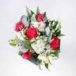 This bouquet feels like a bright Highgate morning captured in flowers, the kind you might see carried home from a local florist after a walk across Waterlow Park. At its heart, velvety red roses open in confident spirals, their rich crimson petals glowing against the softer tones around them. Nestled closely beside them, small snow-white daisies and daisy-like chrysanthemums form a gentle halo, their sunny centres adding a subtle warmth that softens the drama of the red blooms. Red carnations, with their ruffled, feathery folds, deepen the palette, their texture adding a sense of movement as if the bouquet is caught in a quiet breeze drifting up from Highgate High Street. Threads of baby's breath weave between each flower head, tiny white stars that create a cloudlike veil and lend the whole design an airy, celebratory lightness. Eucalyptus stems arc gracefully outwards, their cool grey-green leaves and rounded shapes introducing a modern, almost architectural edge that contrasts with the softness of the petals. Behind and beneath the main flowers, deep tropical greenery fans out in lush, glossy layers, giving the arrangement structure and a sense of abundance without feeling overcrowded. The bouquet appears hand-tied and carefully shaped, compact yet not rigid, as if designed to sit effortlessly on a kitchen table in a Highgate townhouse or on a windowsill overlooking the leafy slopes of Parliament Hill. The mood is one of gentle excitement and heartfelt joy-perfect for congratulations, a long-awaited reunion, or simply welcoming someone home with the fresh scent and uplifting colour of expertly chosen blooms. Every element works together to create a comforting, optimistic presence, like a quiet promise that good things are unfolding right here and now.