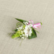 This image presents a close-up view of a delicate wedding corsage or buttonhole laid on a light oatmeal-toned linen that gives the scene a natural, understated backdrop. At its heart is an open white Alstroemeria bloom, often known as Peruvian lily, its petals smooth and slightly fluted at the edges. Inside, fine reddish-brown strokes and speckles catch the eye, adding character and a subtle warmth that contrasts gently with the crisp white. Encircling this central flower are smaller white buds and half-open blossoms, likely from a campanula or lily-of-the-valley type stem, each contributing to a feeling of youthful freshness and new beginnings-perfect for a couple exchanging vows in Highgate. Threads of baby's breath weave lightly among them, their tiny white blooms lending a soft, cloud-like texture that blurs the boundaries between flowers and foliage. On the left, a striking, elongated cone of bright green buds, probably Ornithogalum, rises with a clean, vertical line that introduces both structure and a modern touch. Strong, dark green leaves fan out beneath, grounding the design, while slender arcs of grass-like greenery frame the arrangement, echoing the gentle curves of paths winding through nearby Hampstead Heath. The stems are carefully wrapped together with a glossy, blush-pink satin ribbon, tied into a small, neat bow that brings in a romantic hint of colour without overpowering the calm palette of white and green. The overall effect is one of serenity, care, and considered elegance-a wearable piece of floral artistry created for weddings, proms, and milestone celebrations around Highgate, where classic taste and natural beauty often go hand in hand. Lighting and focus are soft yet precise, highlighting the florist's skill in balancing textures, tones, and proportions.