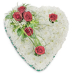 A tender heart-shaped funeral tribute, carefully assembled from a dense, cushion-like bed of hundreds of small, pristine white chrysanthemum blooms, sits against a clean white backdrop. The chrysanthemum surface reads like a soft cloud of petals-tightly packed, gently domed and cool to the eye-signalling purity and quiet remembrance. From the upper left a poignant cluster of three deep crimson roses rests against the white, their velvety petals unfurling fully and releasing a muted, classic rose scent that seems to float above the arrangement. Two more solitary red roses punctuate the composition-one near the right curve and another at the lower point-each given room to breathe with a few discreet green leaves and slender, arching blades that curve around their stems. Interspersed among the foliage are delicate fern-like fronds and glossy broad leaves that add depth and a darker green halo, while a few whisper-thin strands of bear grass extend like calligraphic strokes across the surface. A fine emerald-green satin ribbon neatly trims the heart's perimeter, framing the white chrysanthemum bed with a subtle, respectful edge and lending a touch of formal elegance. The lighting is soft and even, highlighting the texture of the chrysanthemums and the rich, velvety sheen of the roses without harsh shadows. This composition carries a calm dignity-appropriate for a graveside at Highgate Cemetery or a service in nearby Highgate Village-and reads as a symbol of steadfast love and remembrance, made with careful floristry craft and an understanding of local mourning rituals in the Highgate area.