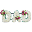A reverent three-dimensional floral tribute spells the word DAD in bold capital letters, each letter built from a dense, cloud-like carpet of pristine white chrysanthemums that read as soft, cushiony texture even at a glance. The white surface is edged all around with a pleated, emerald-green ribbon that gives crisp definition to the letterforms and a quietly elegant contrast to the pale blooms. A low, dark green support bar runs subtly behind the letters, holding them level as a self-standing memorial display. Nestled into each letter are small, carefully placed clusters of deep fuchsia to magenta roses - some buds tight, some beginning to unfurl - paired with tiny white freesias or delicate spray blooms and rich dark foliage for depth. The first D bears its cluster on the upper left curve, the A's cluster sits tucked into the lower center V, and the final D mirrors the first with its accent on the upper right curve; these placements create a gentle visual rhythm and personal, handcrafted balance. The overall effect is one of respectful simplicity: pure white blooms suggest peace and remembrance, the green trim echoes steadiness, and the magenta roses offer a quiet note of affectionate warmth. Soft, diffuse lighting on a clean white background highlights textures and the handcrafted finish, while a faint scent of chrysanthemum and rose might hang in the air. This arrangement is intended for funeral or graveside use, a dignified, personal tribute appropriate for services in Highgate and nearby cemeteries such as Highgate Cemetery or small chapels in the area, suitable for local delivery and careful placement by an experienced florist.