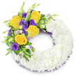 A carefully shaped circular sympathy wreath, pictured against a clean white backdrop, that reads as a quiet, hand-crafted 'O' of remembrance. The main body is built from hundreds of small, pristine white spray chrysanthemums packed so closely their overlapping petals form a soft, cloud-like band-cool to the eye and supple to the touch-evoking calm and reverence. Along the upper left curve a thoughtful cluster of colour rises like a quiet greeting: several fully opened, golden-yellow roses with buttery, spiralled petals, their faint rose perfume almost evident, sit beside deep royal purple lisianthus (Eustoma) whose ruffled, cup-shaped blooms offer velvety contrast. A few paler lavender lisianthus buds tuck in among the flowers, lending depth and the suggestion of things still unfolding. Fresh green foliage-glossy rounded leaves, lightly variegated stems and delicate fern fronds-frames and supports the spray, its varied textures setting off the vivid palette. Look closely and you'll notice a subtle dark purple mesh or crinoline ribbon peeking from beneath the chrysanthemum ring, tracking the inner and outer edges and echoing the lisianthus tones in a restrained, elegant way. The composition feels intentional and tender; the white base carries a sense of peace while the yellow and purple accents read as warmth and dignity. As a local Highgate florist might describe it, this wreath is suited for Highgate Cemetery services or a quiet tribute placed near Waterlow Park, offering a handcrafted expression of condolence that honours memory with measured beauty and gentle craftsmanship.