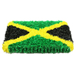 Here, a Jamaican flag-inspired funeral tribute is presented as a striking, three-dimensional floral panel against a pristine white background, its bold colour blocks and textures immediately commanding attention. The entire rectangular surface is covered with countless tiny, ruffled petal shapes or fabric florets, laid so densely they create a plush, tactile field that looks almost like a work of modern textile art. A vivid golden-yellow X runs diagonally from corner to corner, the saltire clean and precise, evoking beams of light crossing over one another in a quiet chapel off Highgate High Street. Between these glowing bands, the upper and lower triangles are a full, vibrant green, the clustered petals giving the impression of thick groundcover or moss along a shaded pathway in Waterlow Park. The left and right sections are rendered in deep black, softly matt and gently shadowed, adding a sober, reflective quality that grounds the tribute and makes it especially fitting for a farewell. Bright, even lighting falls across the panel, highlighting each curve, crease, and overlap of the material, so that the viewer can sense not only the colours but the hours of careful, deliberate work behind them. The flag panel is visibly thick, resembling a decorative plaque or board that could stand beside the coffin or at the entrance to a memorial gathering. It powerfully references Jamaica's national symbol while sitting comfortably in a North London setting, perhaps created for a family in Highgate wishing to honour a loved one's island roots. The overall mood is one of pride, reverence, and heartfelt remembrance, expressed through disciplined lines and richly layered texture.