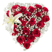 A densely packed heart-shaped spray of flowers sits against a pristine white background, its silhouette carved from dozens of deep crimson roses. The roses range from tight buds to fully unfurled blossoms, their velvety petals catching soft light and throwing gentle shadows that deepen the red into almost wine-toned richness. Between and around the larger blooms, feathery clusters of tiny white baby's breath (Gypsophila) weave like a soft mist, lending an airy halo and a delicate, starry texture that brightens the composition. Tucked into the upper left curve of the heart is a single, sculptural white lily: broad, waxy petals edged in pure white with a faint creamy yellow near the throat and a row of warm yellow stamens at its centre. The lily's sleek form contrasts beautifully with the rounded roses and the whisper-like gypsophila, offering a moment of calm serenity amid the passionate reds. A subtle bouquet perfume is almost imaginable here - the sweet, heady scent of roses balanced by a faint, clean lily note - as if arranged in the cool morning light that filters through Highgate's narrow lanes. The florist's careful hand is evident in the precise heart outline and the balanced play of texture and colour, making this design suitable for declarations of love, anniversaries, memorial tributes, or elegant sympathy. The white backdrop isolates every detail so you can sense the craftsmanship: how each rose was chosen for depth, how the gypsophila softens the edges, and how the single lily reads like a thoughtful punctuation mark of purity and hope.