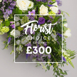 From Flowers Highgate, a lush Florist Choice Spray sits as a grand tribute, its abundant blooms arranged in a generous cascade against a soft, neutral grey backdrop. A crisp white rectangular panel centers the design, bearing Florist CHOICE SPRAY in elegant script and the price ?300 in bold, marking this as a premium, pre-designed arrangement for meaningful occasions. The palette is a refined mix of ivory-white roses, pure white lisianthus, and the airy notes of white freesias, punctuated by rich purple blooms that catch the eye. Deep purple lisianthus mingle with lavender-hued eustoma and freesias, while tall spikes of purple veronica or delphinium add vertical line and drama. Sprigs of smaller lavender limonium provide delicate texture, and a verdant chorus of ferns and glossy leaves weave throughout, with light-green viburnum clusters glinting like fresh buds among the greenery. The overall form is opulent yet balanced, a generous spray that speaks of elegance and timeless sympathy. Gentle studio light bathes the arrangement in a soft glow, inviting reverence and quiet reflection. Delivered across Highgate and nearby neighbourhoods such as Crouch End, Muswell Hill, and Archway, this premium spray suits sympathy tributes, funeral flowers, or a grand celebratory gesture, and bears the mark of a seasoned local florist. The scent blends rose and freesia with a subtle green breath from the viburnum, and the craftsmanship radiates quality, care, and a heartfelt connection between giver and recipient.