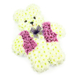This photograph captures a carefully constructed floral teddy bear, a gentle funeral tribute that looks as though it might be carried along Highgate's leafy streets to a quiet chapel or family gathering. The bear is entirely made from creamy white chrysanthemums, their tightly packed petals forming a thick, plush coat over the head, body, and limbs. The rounded face is especially expressive: two small, dark eyes are set close together, shining softly against the matte softness of the petals, while a petite black nose sits at the centre of the muzzle. Below, an understated smile is suggested by the placement of the blooms, giving the bear a nurturing, almost protective expression. The body is broad and cuddly, with a generous tummy and short legs that rest firmly, as if the bear is seated. Across its chest, a floral waistcoat is fashioned from deep pink and lilac-toned flowers, grouped together in two symmetrical side panels that form a clear V down the centre, adding visual interest and contrast. At the top of this vest, a bow of fine purple netting is tied neatly, its semi-transparent loops spilling gently over the surrounding flowers, creating an elegant yet playful detail. The image is composed against a simple, plain white background, with gentle, even lighting that highlights the textures without harsh shadows. Ideal as a child's funeral tribute or a tender memorial gesture in Highgate and nearby areas like Archway or Hampstead, this teddy bear design expresses softness, love, and the wish to wrap someone dearly missed in a final, comforting floral embrace.